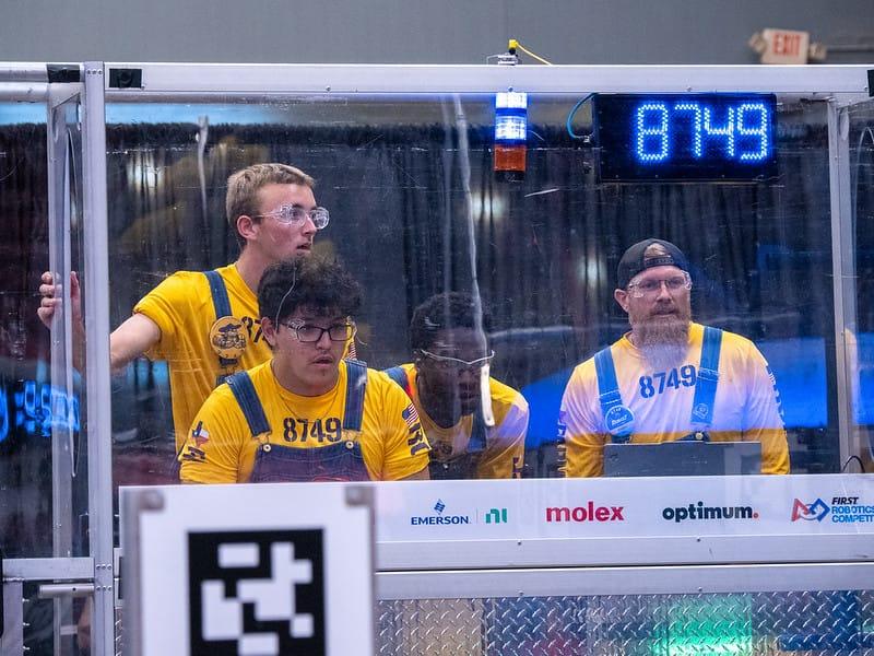 A FIRST Robotics Competition drive team at the driver station, match clock overhead