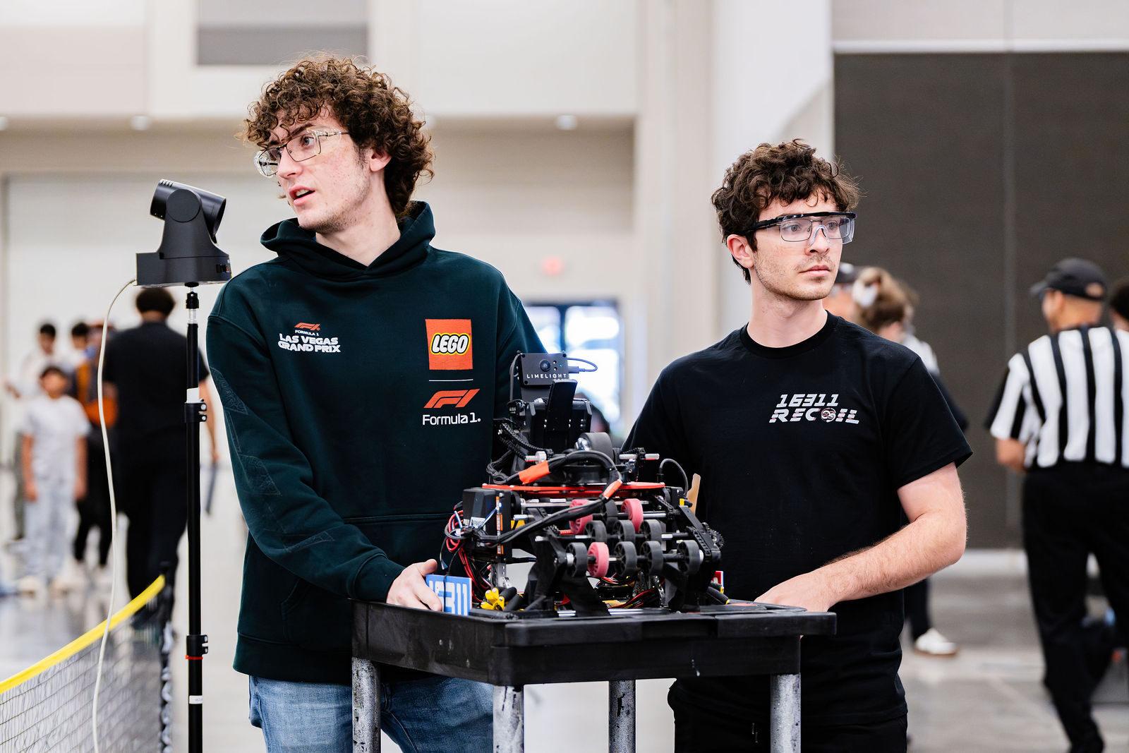 Two FIRST Tech Challenge team members wheeling their robot to the field on a cart
