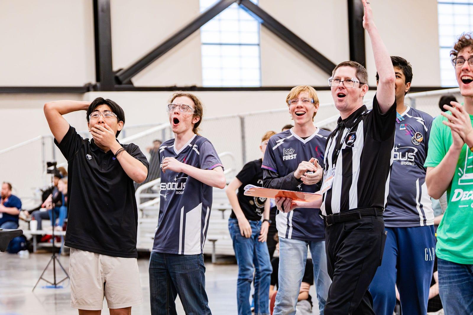 A FIRST Tech Challenge team and a referee cheering a match result at the Texas Cup