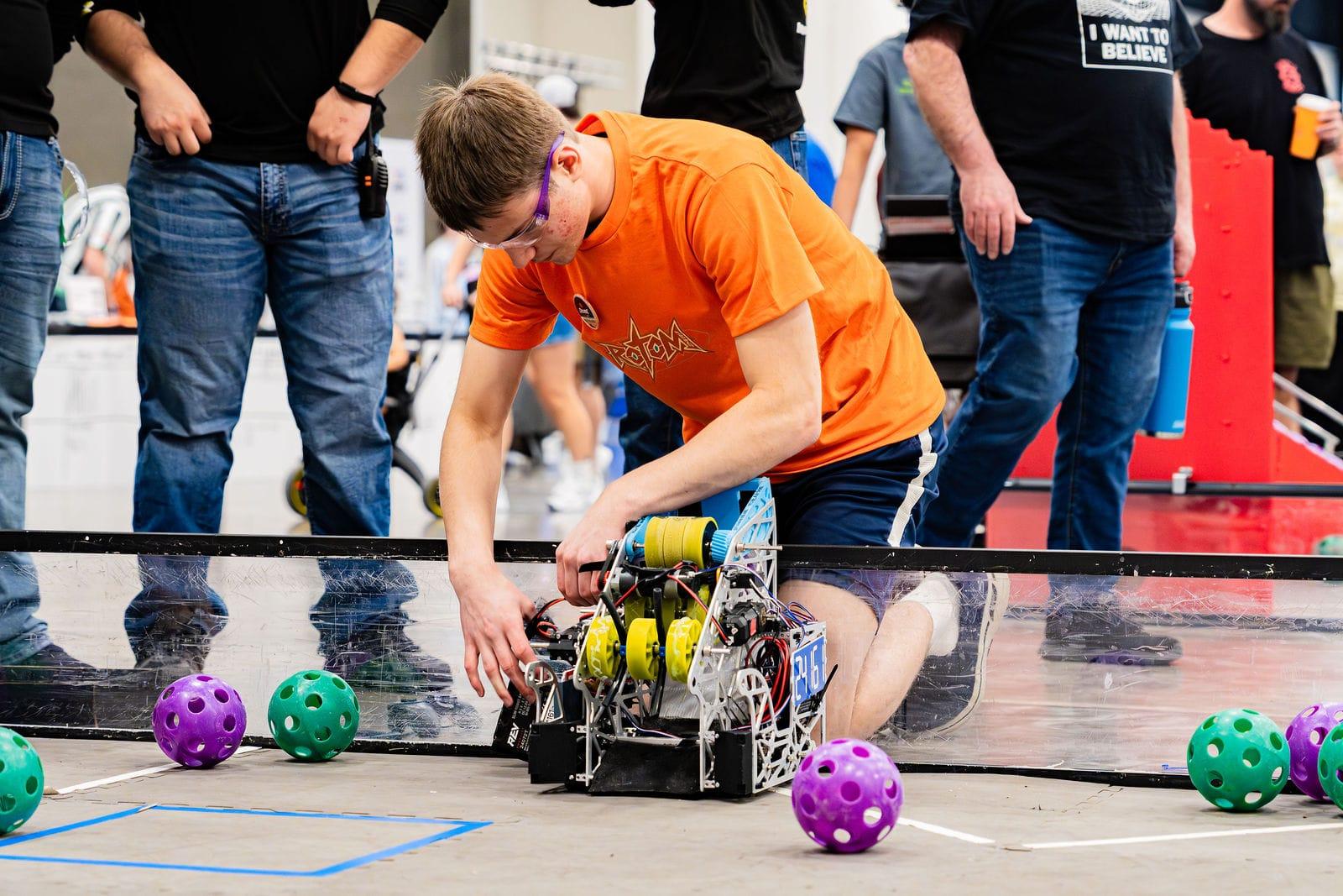 A FIRST Tech Challenge student setting his robot down on the field at the Texas Cup